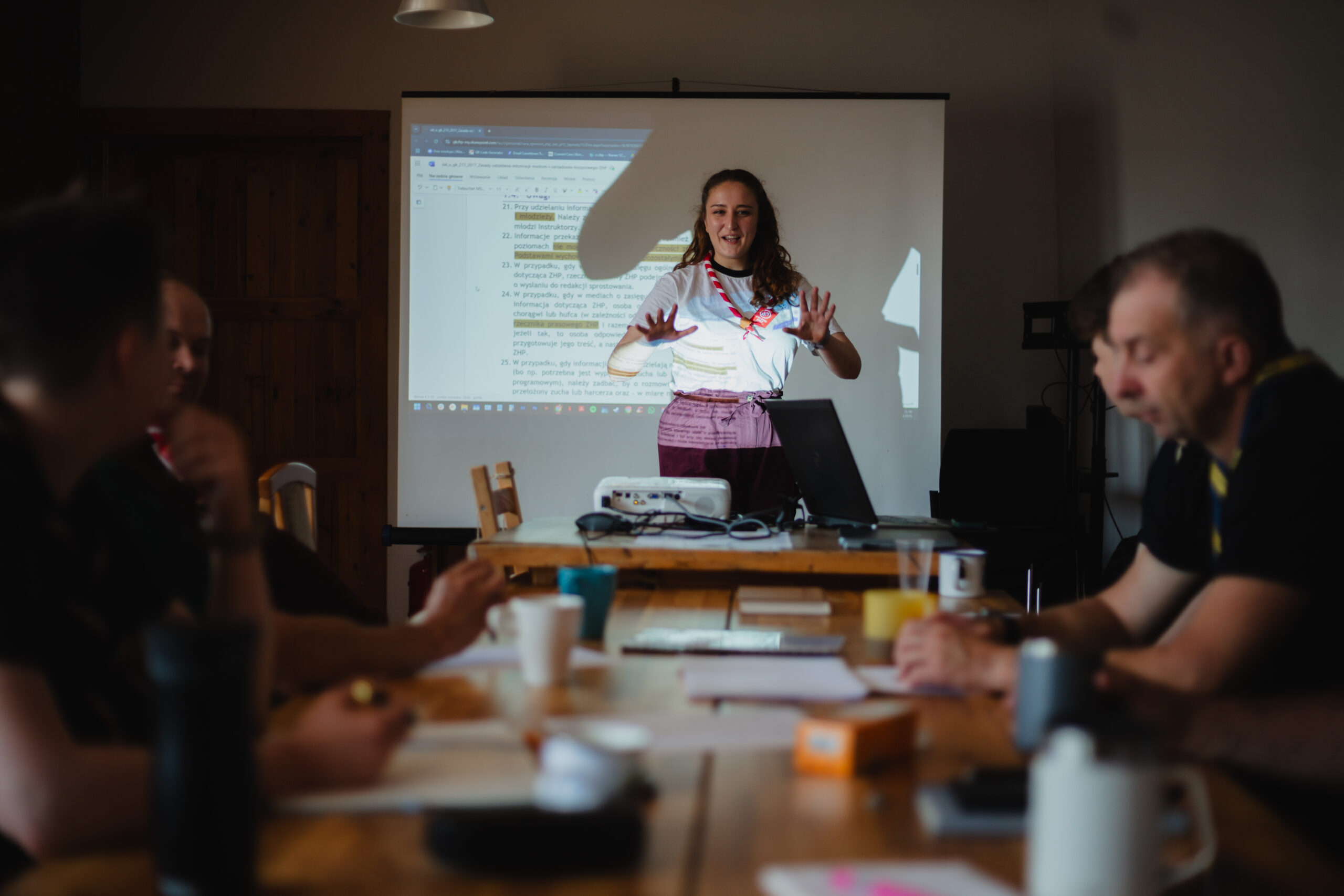 Model kompetencji ZHP, instruktorzy ZHP podczas szkolenia, prowadząca szkolenie stoi na tle ekranu i tłumaczy.